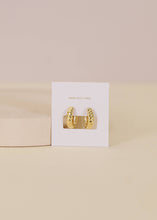 Load image into Gallery viewer, Gold hoop earrings against a beige background
