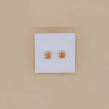 Load image into Gallery viewer, Pair of gold stud earrings on a 'TANAKELLY' branded card against a beige background