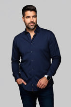 Load image into Gallery viewer, Man wearing a dark blue tobacco patterned shirt against a grey solid wall.
