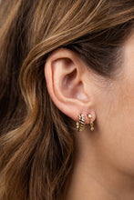 Load image into Gallery viewer, Close-up of a person wearing gold hoop earrings with a neutral background